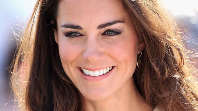 Kate Middleton laughing, with long hair and a cream top