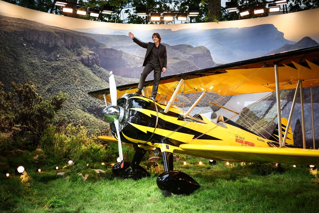 man on top of plane in front of screen 