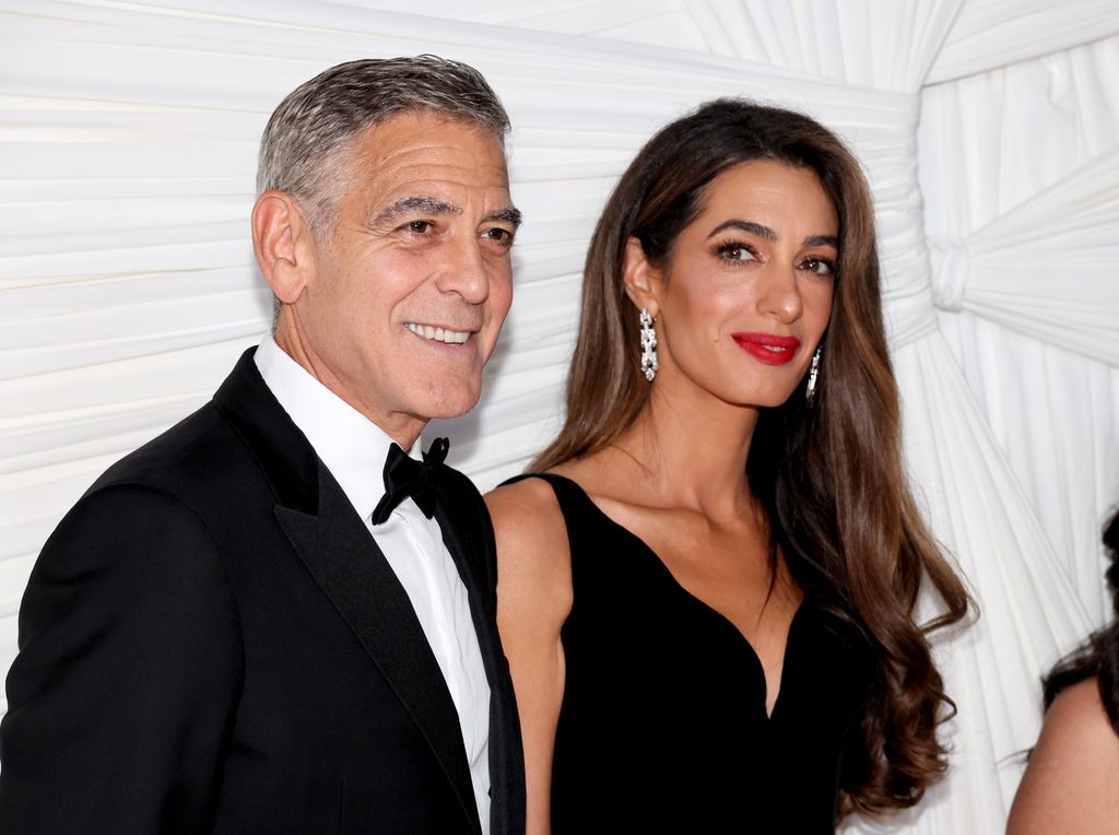 George and Amal Clooney smiling while standing side by side