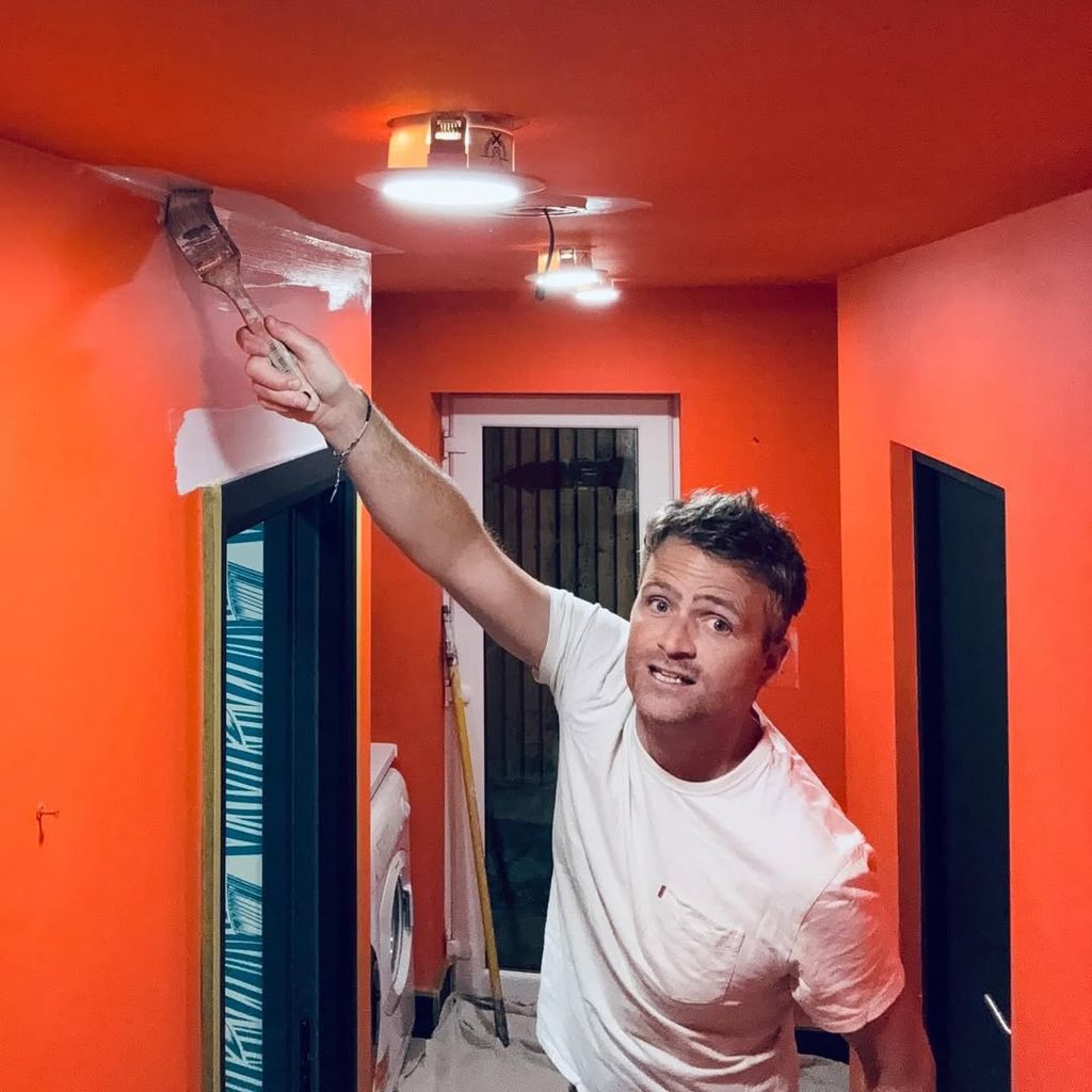 Ben Hillman painting an orange wall white