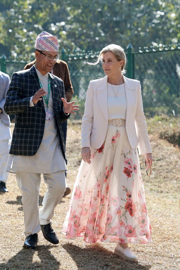 Sophie in floral skirt walking with nepalese man
