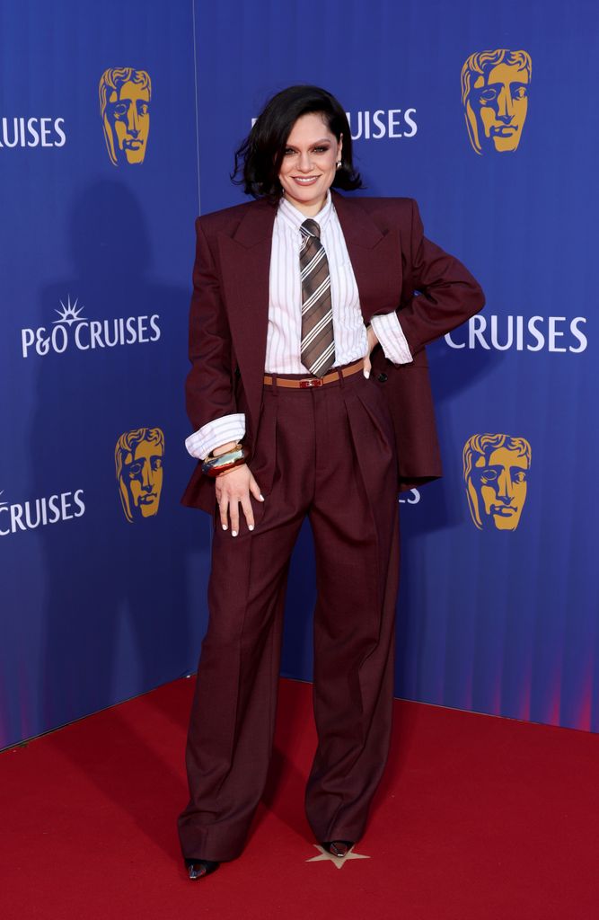 Jessie J in a deep red suit and tie on the red carpet