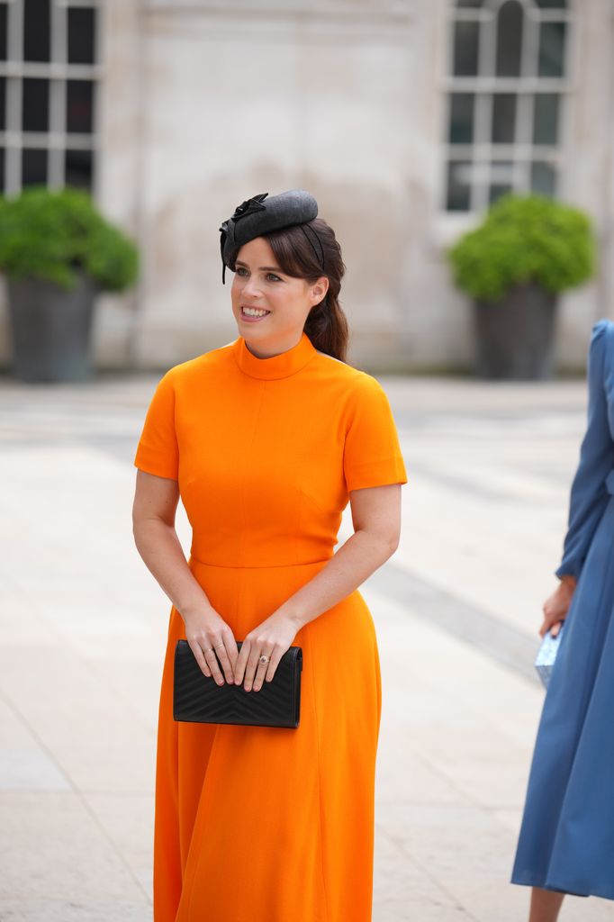 Princess Eugenie wearing orange dress and black hat