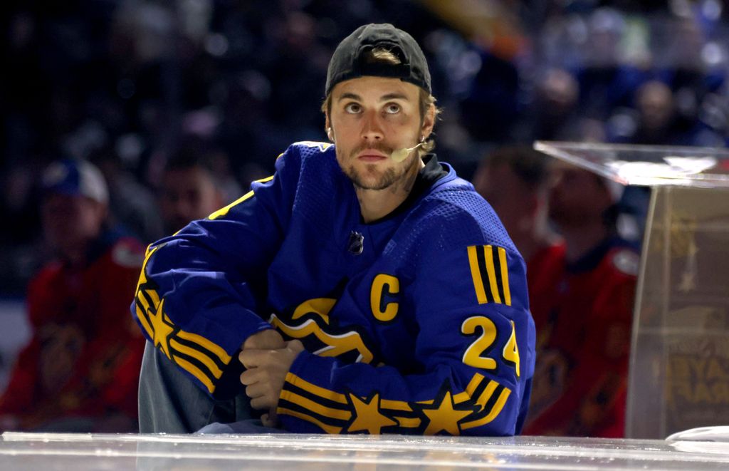 Justin Bieber wearing a cap and blue jersey as he plays hockey match