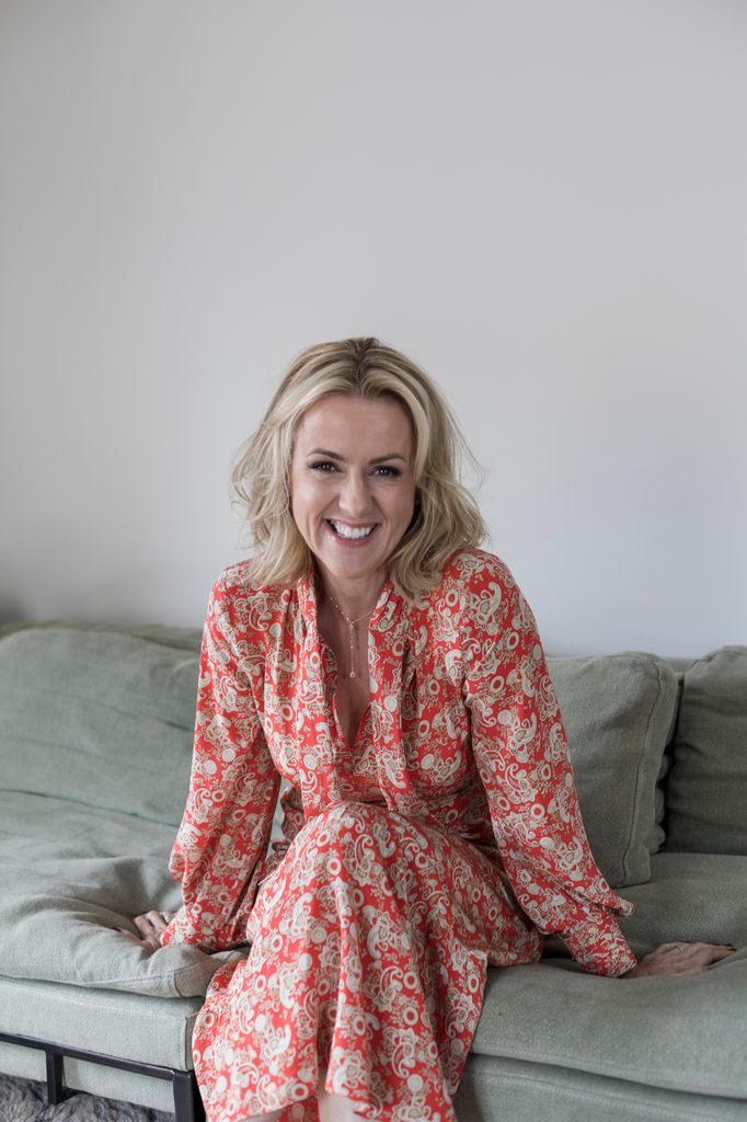 Jojo Moyes in a floral print dress on a soft sofa 
