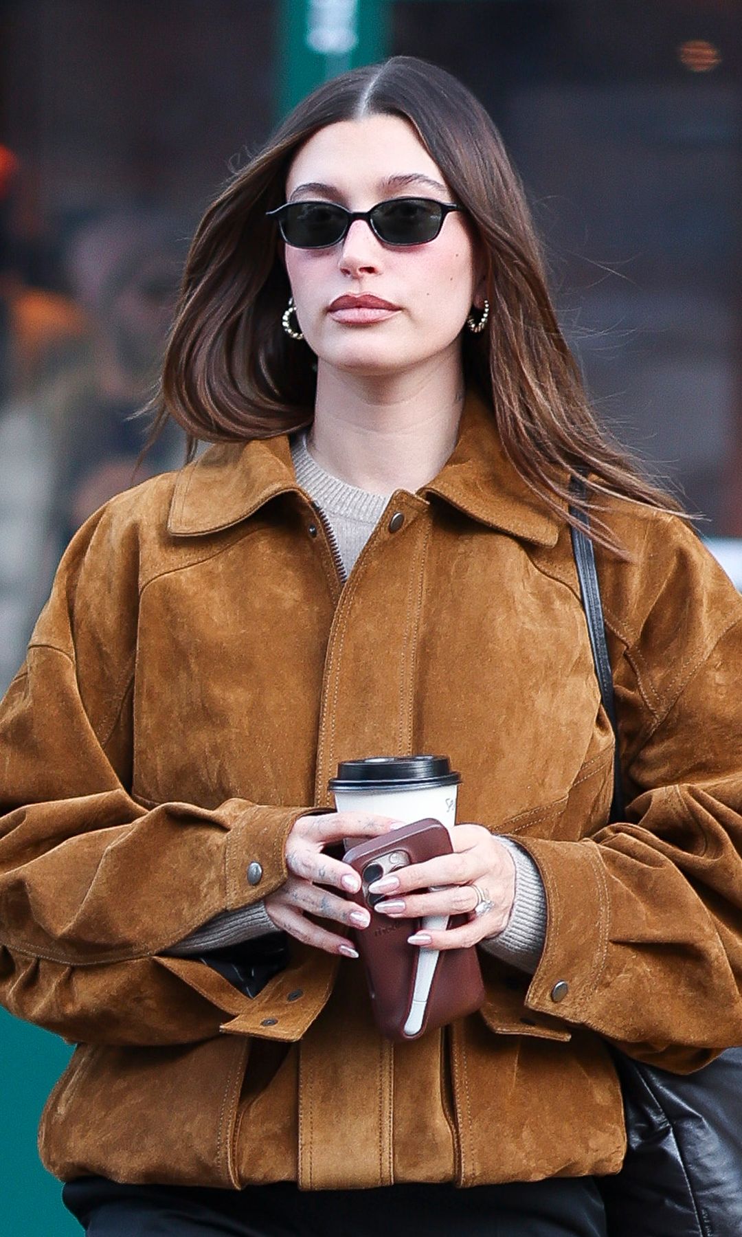 Hailey Bieber seen in SoHo on January 30, 2025 in New York City walking down the street in a suede tan jacket, sunglasses and black trousers