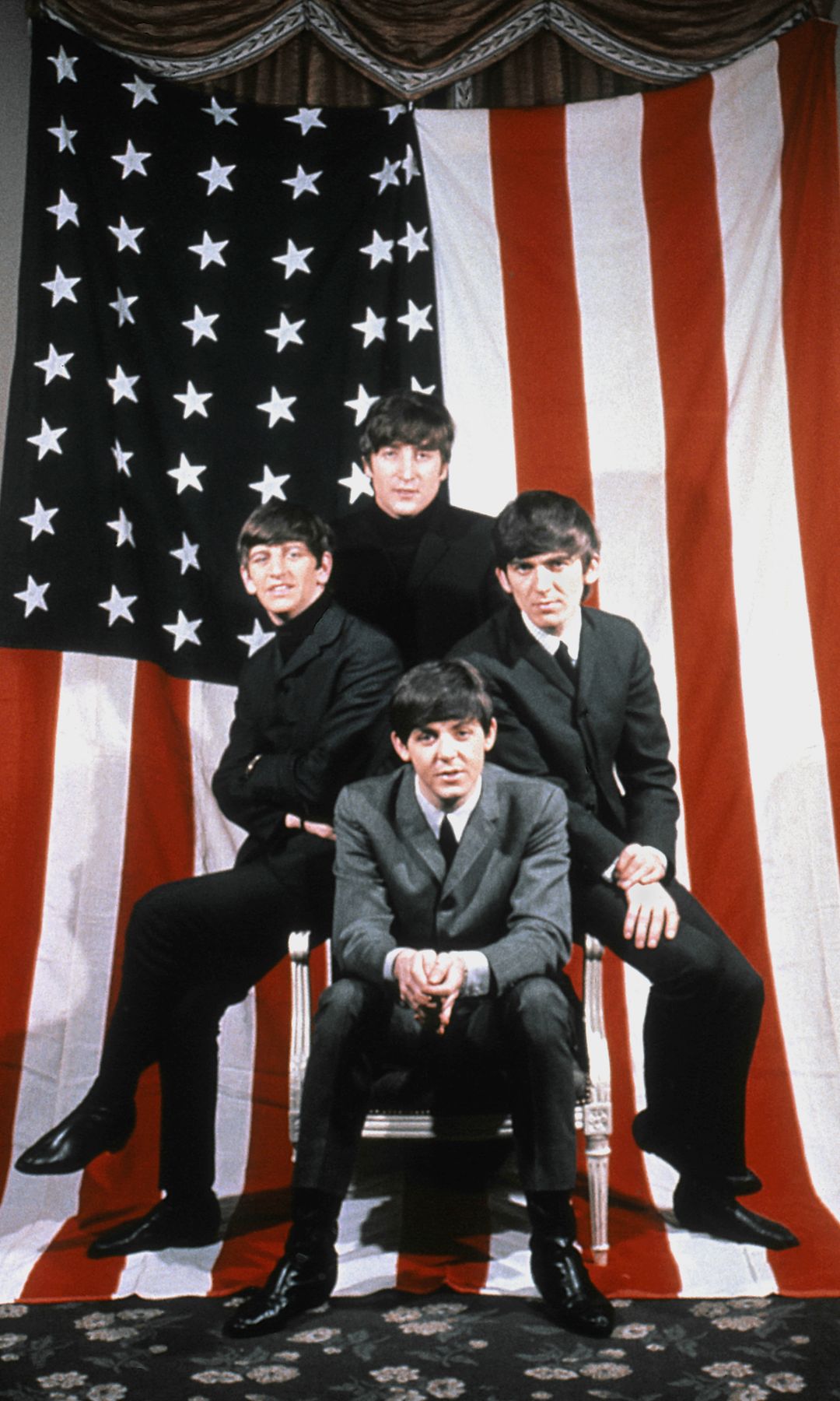 In front of a massive American flag, the Beatles pose like a power stack—Paul seated in front, the others perched behind. It screams “We’ve landed,” and boy, they had.