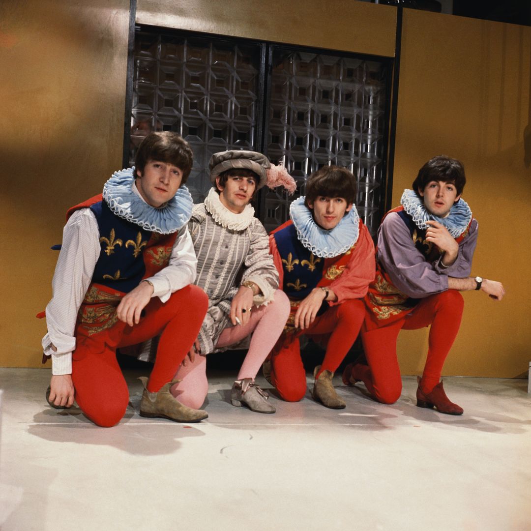 The Fab Four don Elizabethan costumes with ruffled collars, bright tights, and embroidered tunics. They’re crouched in a theatrical pose, looking like Shakespearean jesters with guitars instead of lutes.